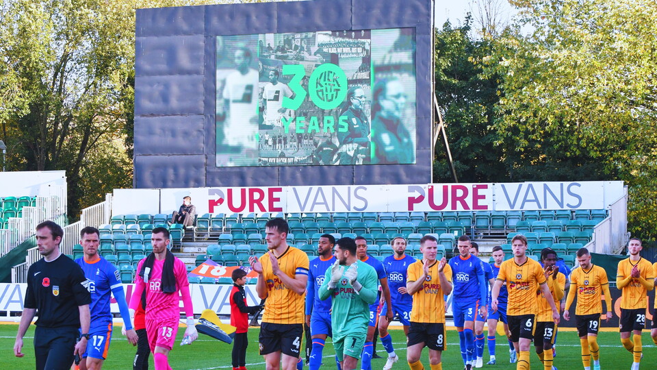 Players walk out of the tunnel in front of big screen
