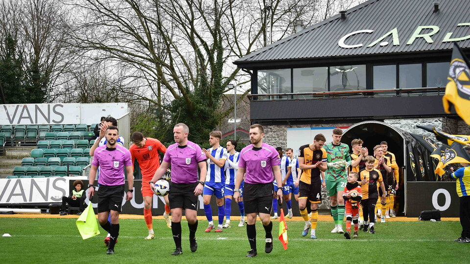 Newport v Colchester teams arriving on pitch.