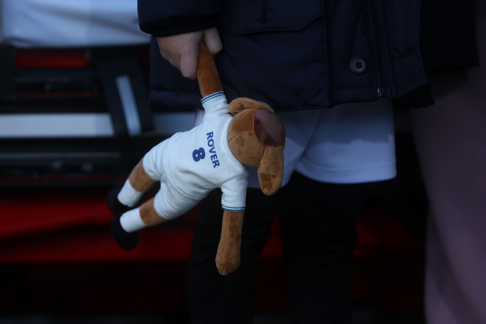 A young Tranmere Rovers holds a Tranmere Rovers mascot 'Rover' teddy